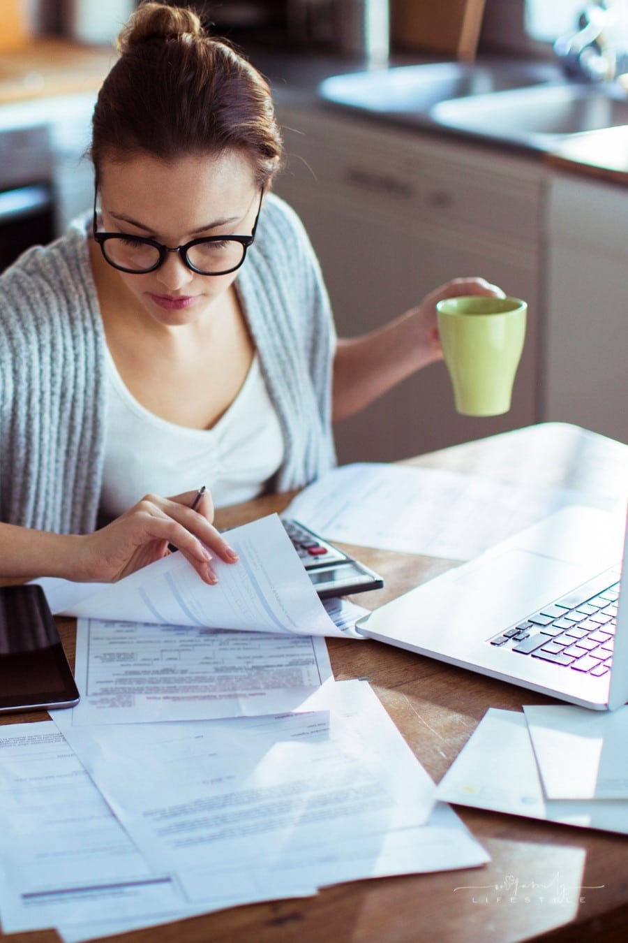 woman looking at bills with coffee mug in hand