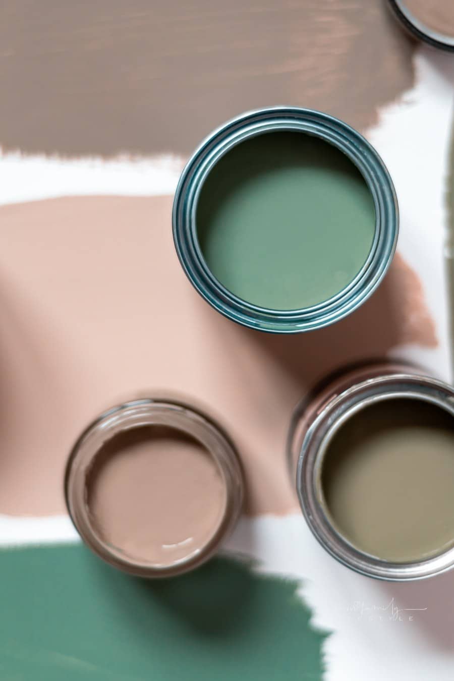 Tiny sample paint cans during house renovation, process of choosing paint for the walls, different green colors, color charts on background