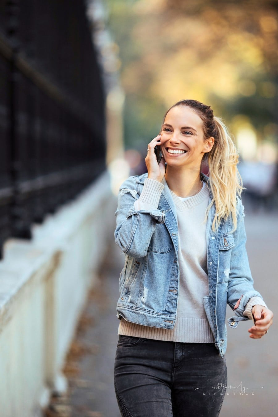 blond woman smiling with pearly white teeth while on phone