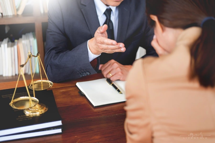 lawyer talking to woman who has head in her hands