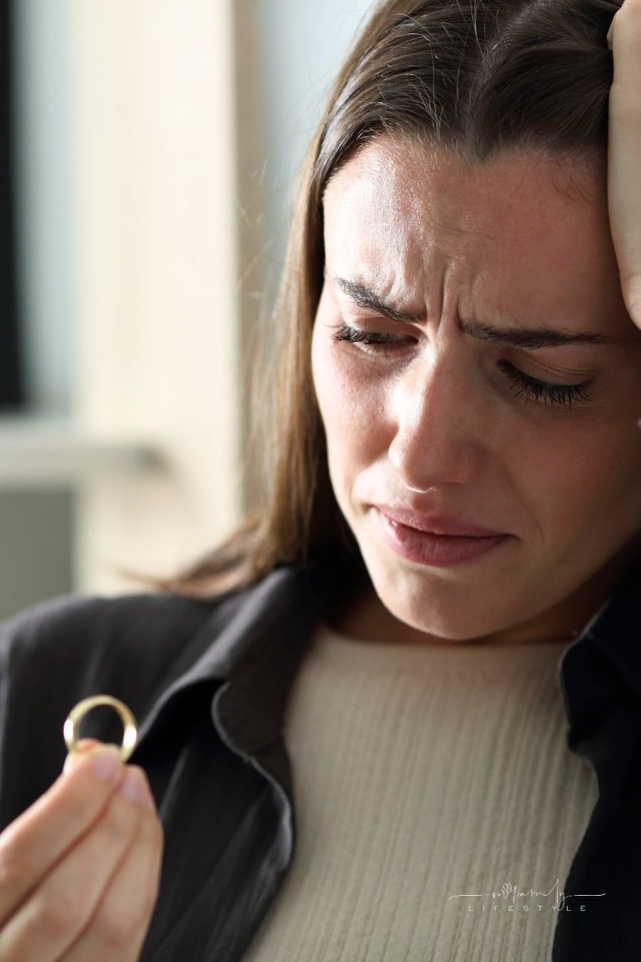 sad woman looking at wedding ring in her hand