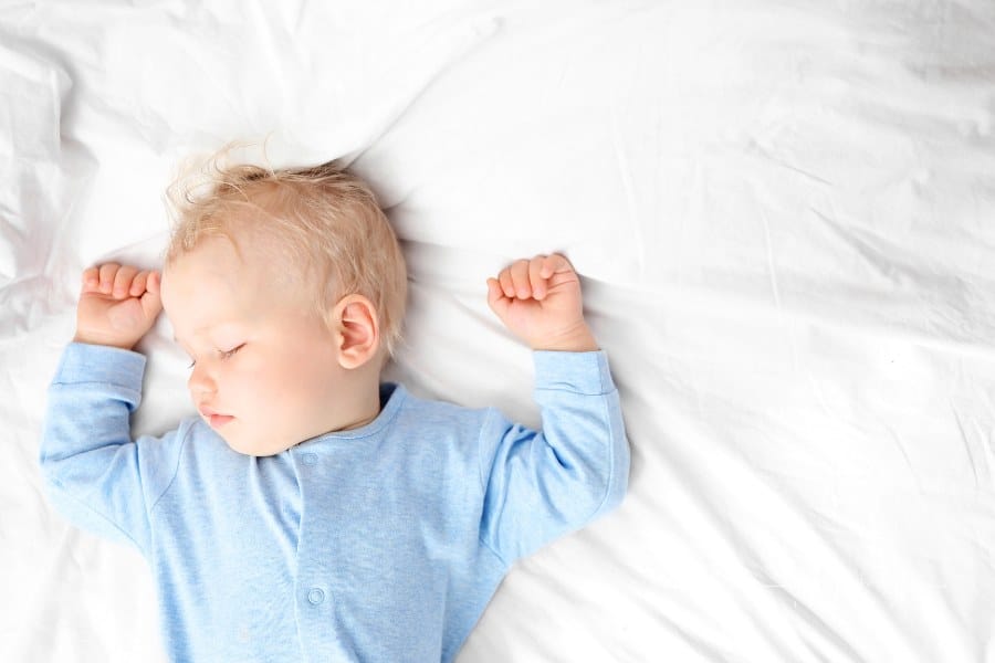 Baby boy sleeping on sed in blue pajamas