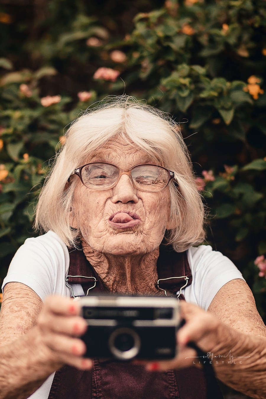 Elderly Woman taking Selfie with vintage camera while sticking tongue out
