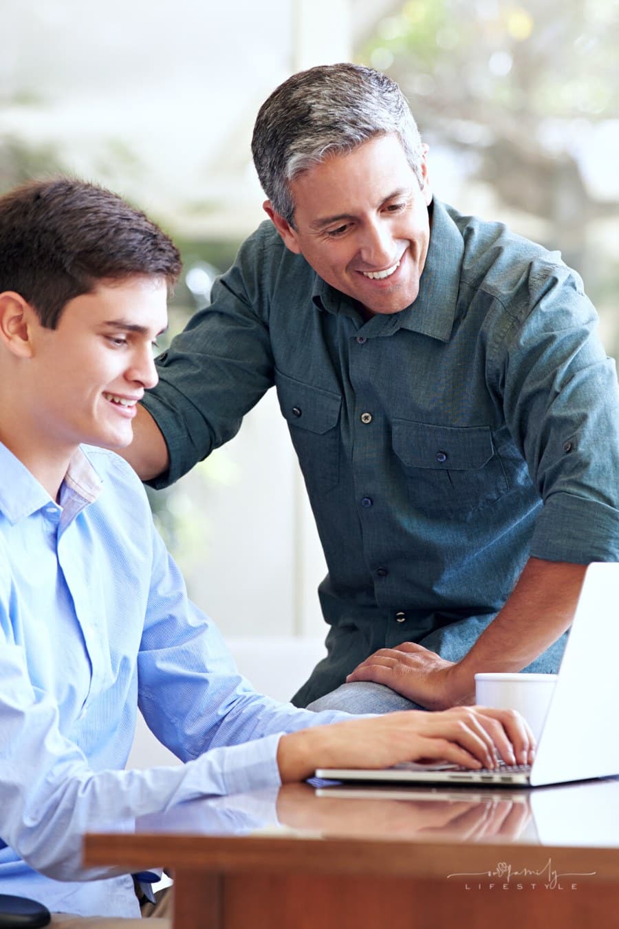 father and teenage son looking at laptop together