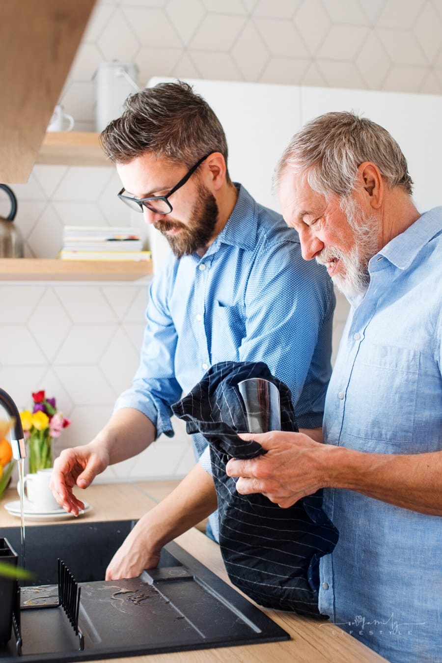elderly father washing dishes with adult son