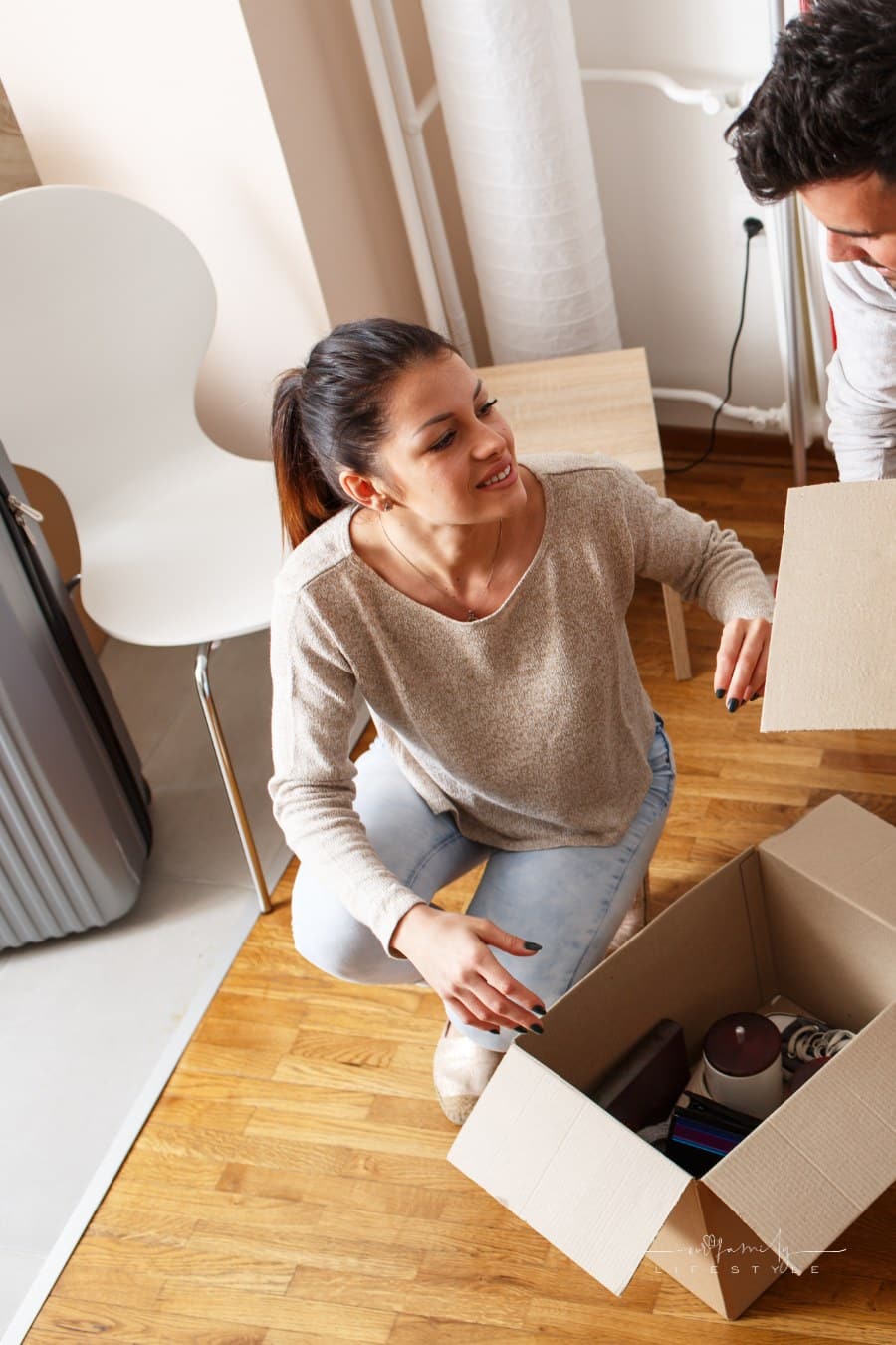 young couple packing to move with luggage in background
