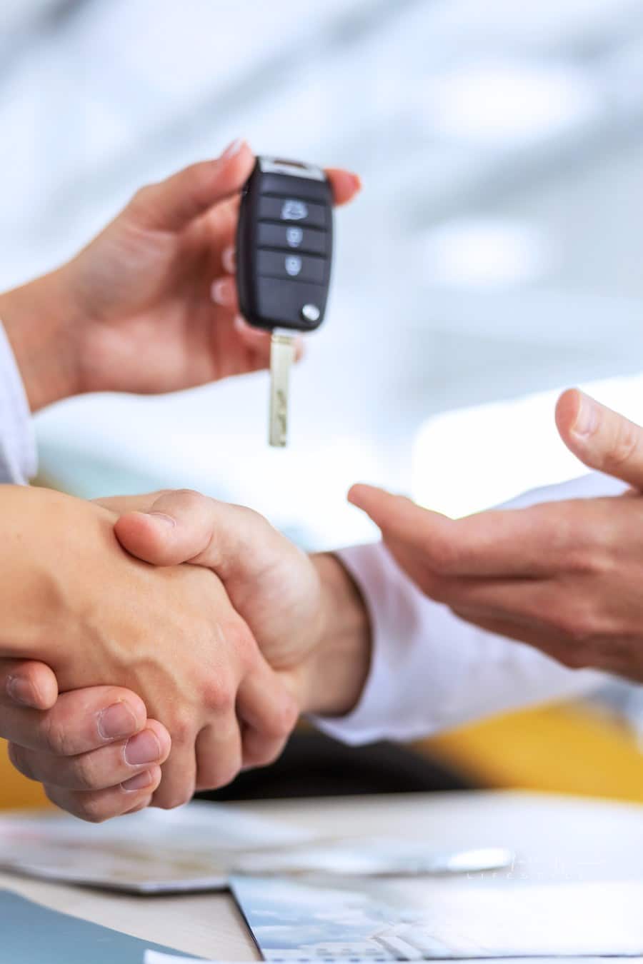 Closeup of car seller and buyer shaking hands. Car seller handing a car keys to a buyer.