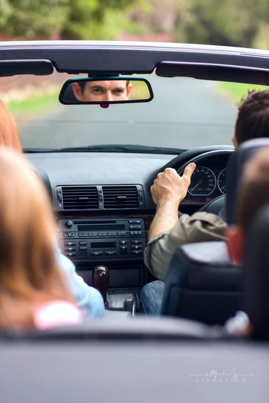family on vacation in rented convertible with dad looking at kid's in rearview mirror