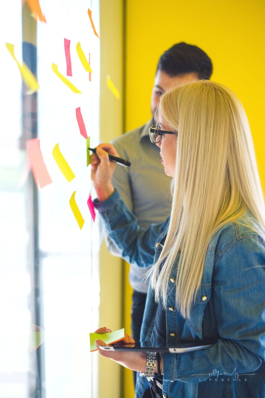 man and women writing on sticky notes during brainstorming session