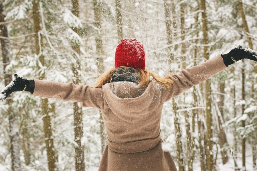 Woman Wearing Brown Coat with her amrs open standing in the snow