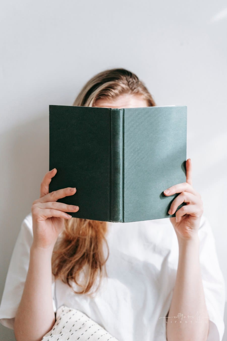 woman reading while holding book in front of her face