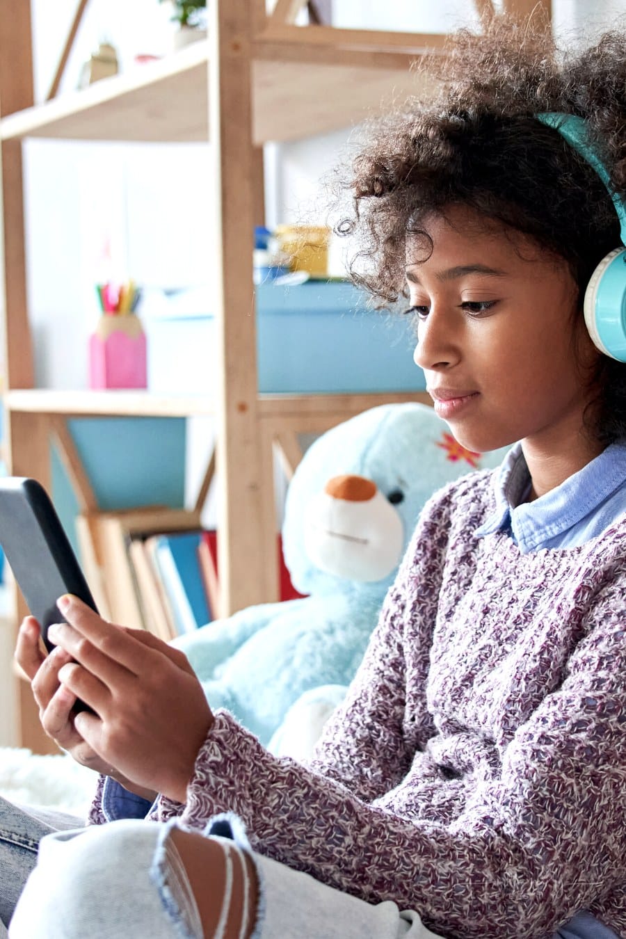 girl wearing headphones while holding phone