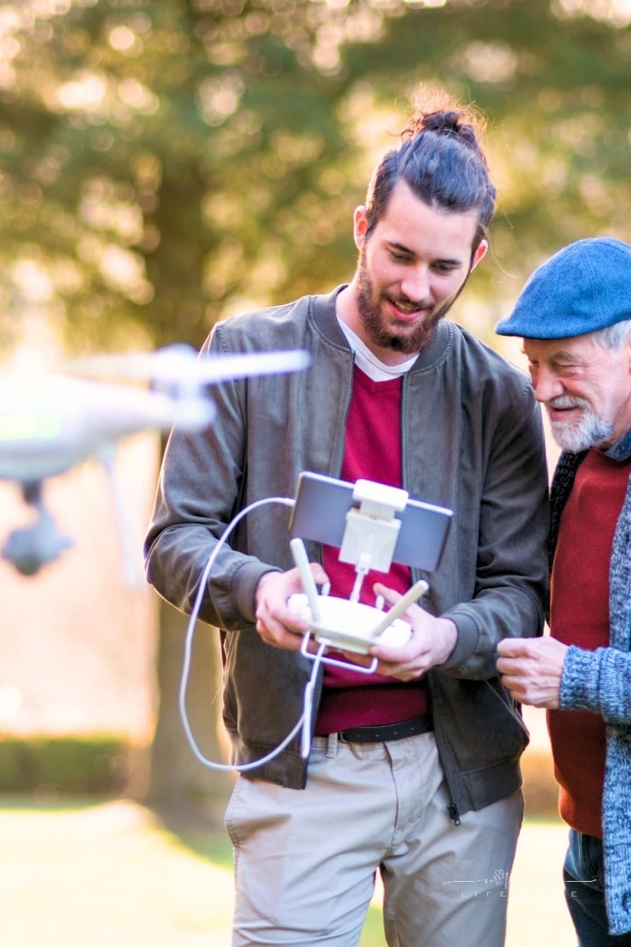 adult son showing his senior father how to use a drone