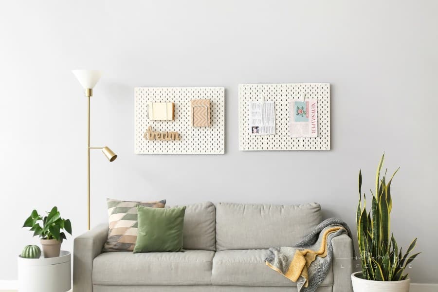 Comfortable Sofa near Grey Wall with Pegboards in Living Room Interior