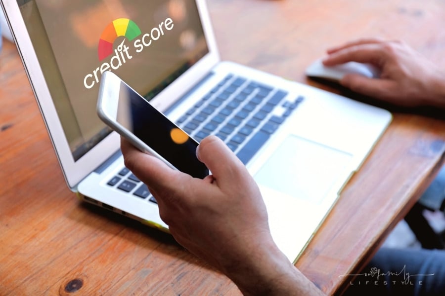 man looking at credit score on laptop with phone in hand
