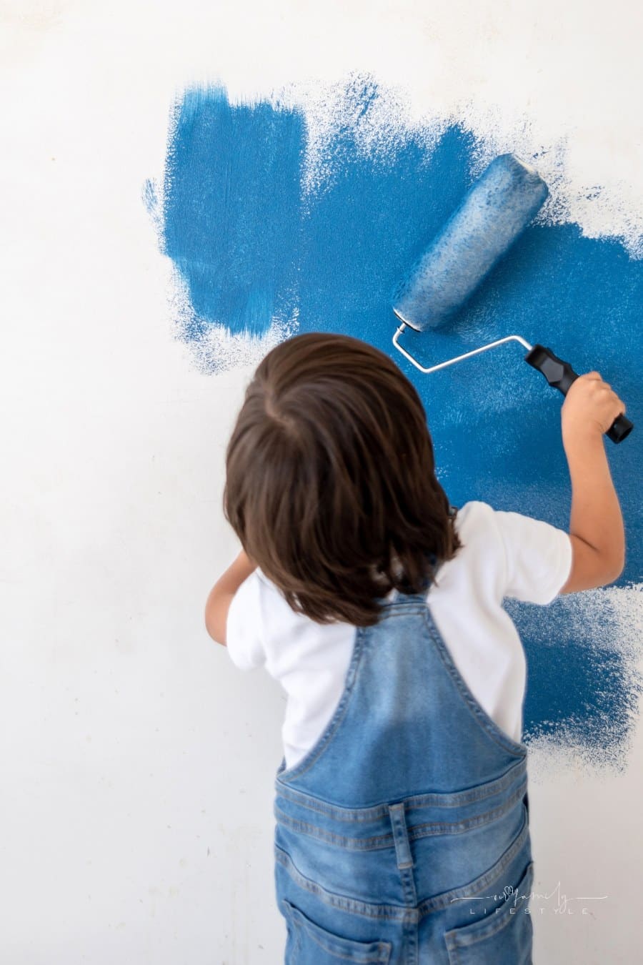 Boy painting his room blue and holding a roller - home improvement concepts