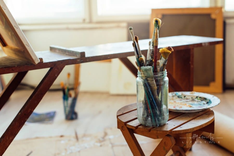 Photo of a bright art studio with big windows and painting equipment