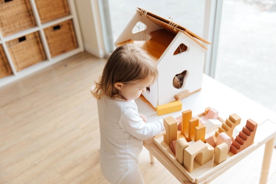 toddler girl playing with wooden blocks