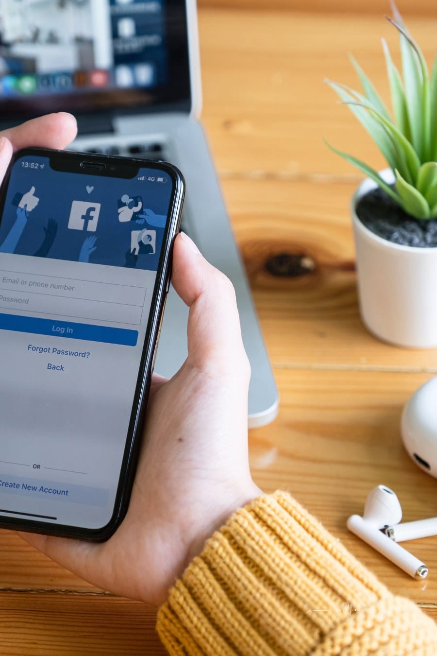 woman.s hand holding a smartphone with Facebook login screen