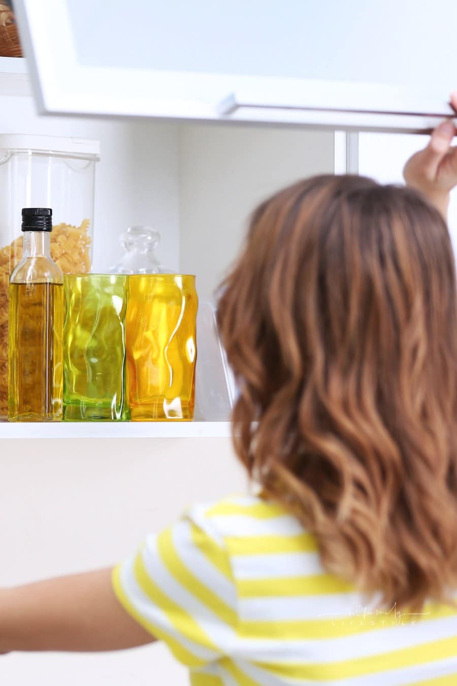 Woman Looking at Items Inside Open Kitchen Cabinet