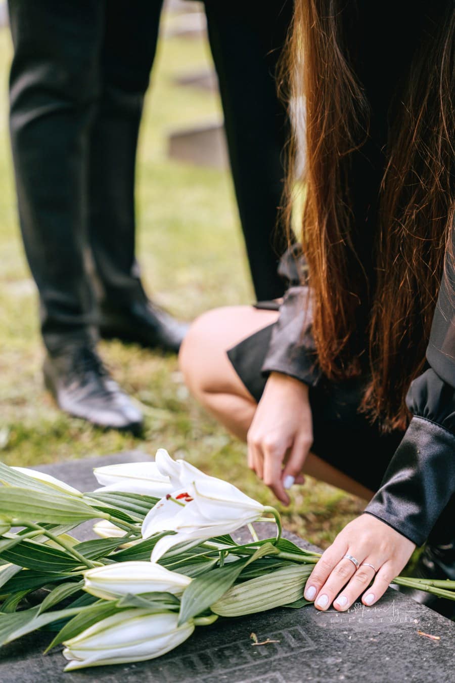 A Close-Up Shot of a Person Putting Flowers on a Headstone