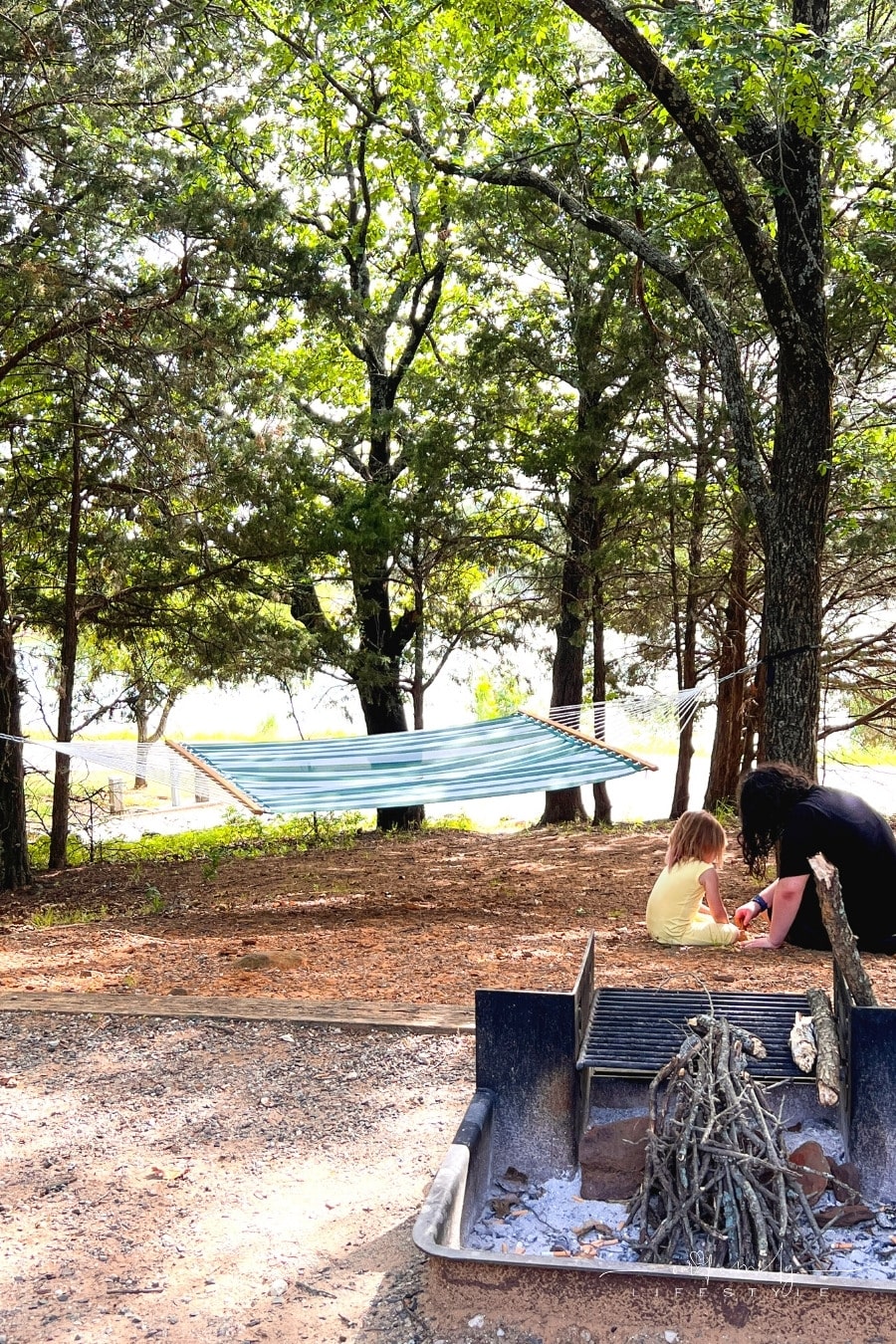 kids digging in dirt in front of campfire pit with hammock hanging in background