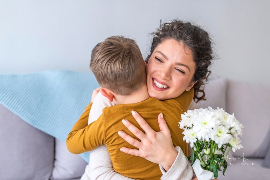 child giving mom a hug after presenting her with a bouquet of flowers gift
