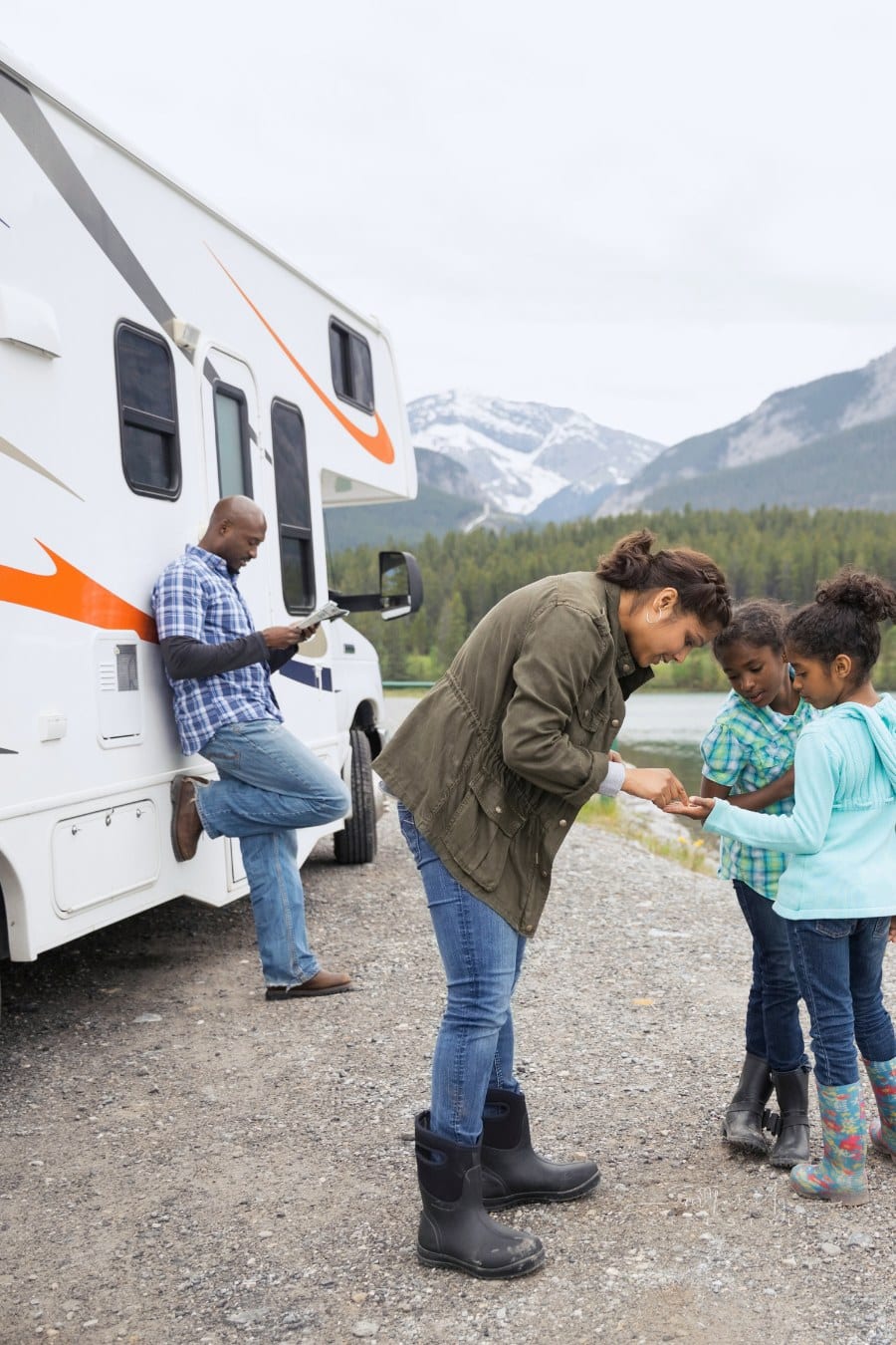 Family standing at lakeside near RV