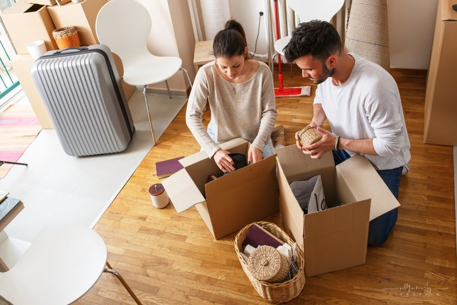 young couple packing to move with luggage in background