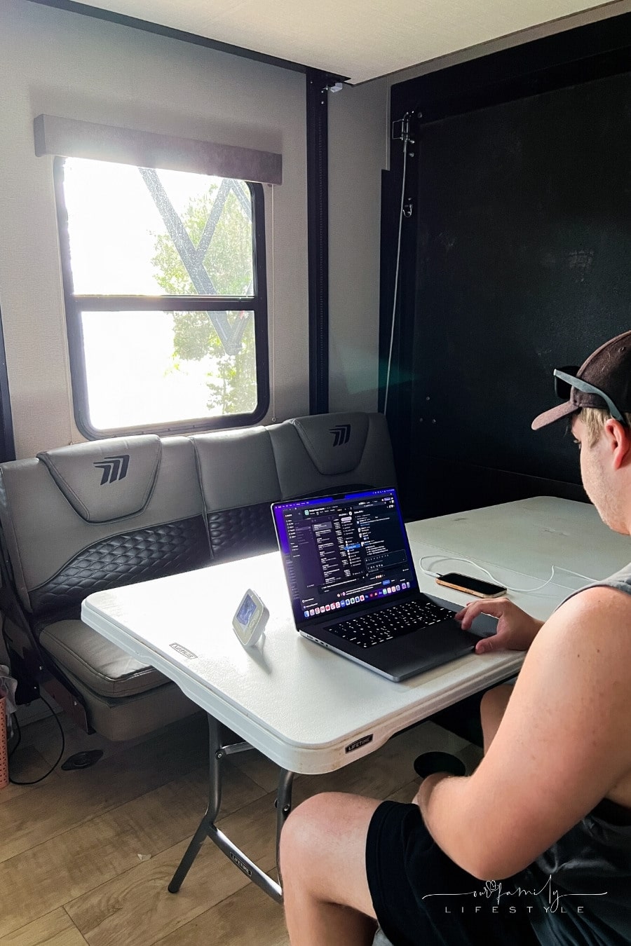 man working at laptop sitting inside a rv trailer toy hauler