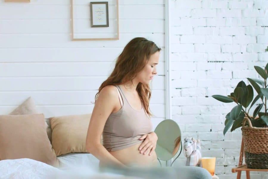 Closeup expectant mother suffering nausea in bedroom. Pregnant trying tea to help morning sickness.