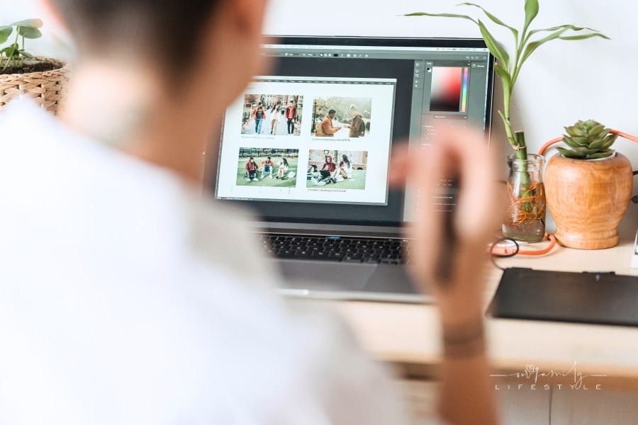 Woman sitting at table with laptop and editing photos