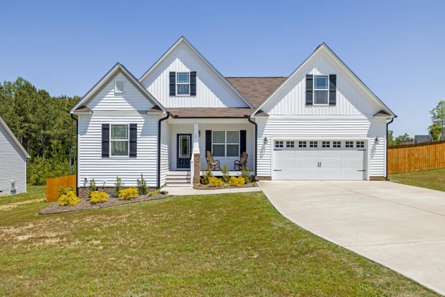 Modern white family home with garage, front yard, and blue sky background.