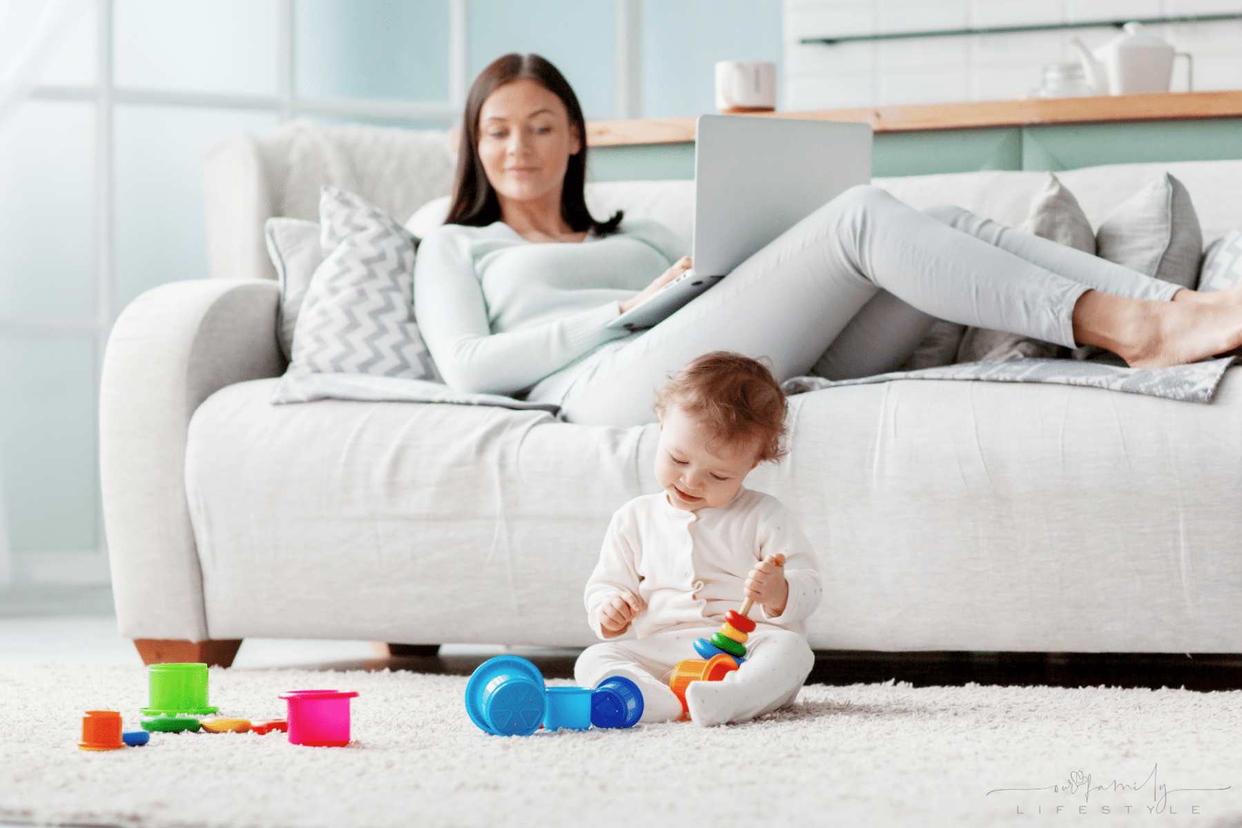 mom-works-laptop-home-while-her-child-plays-with-toys-floor