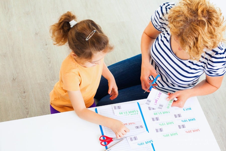 daughter helping mom cut grocery coupons