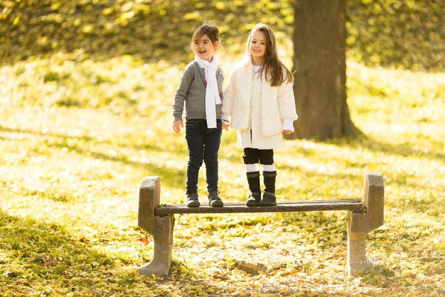two girls on a park bench during autumn