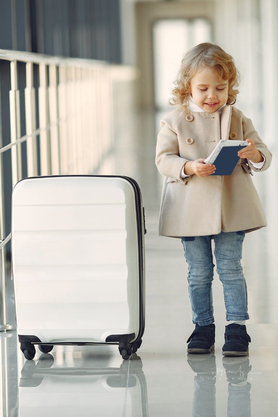 Child at the airport. Little girl with a suitcase. Girl in brown coat holding passport