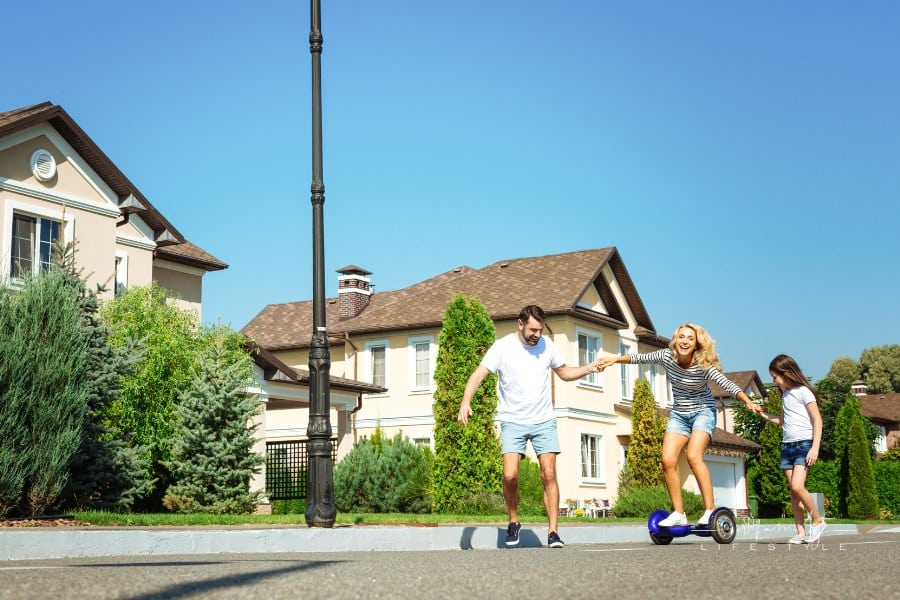 Caring man and daughter helping mother riding hoverboard