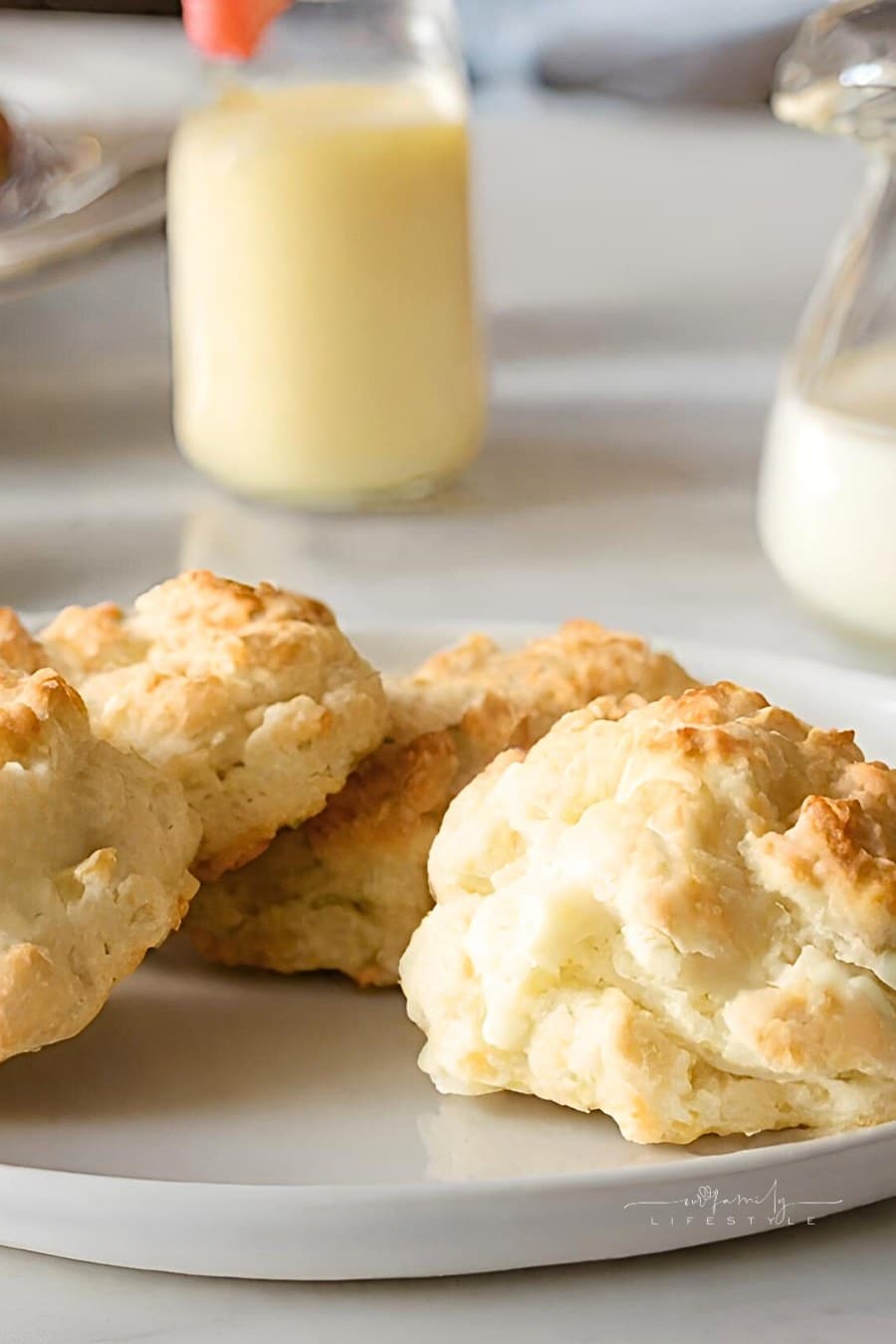 homemade biscuits on a plate with milk and juice in the background