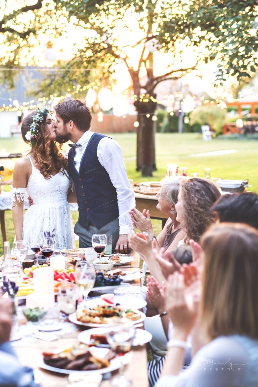 bride and groom kissing at head of table at outdoor wedding reception