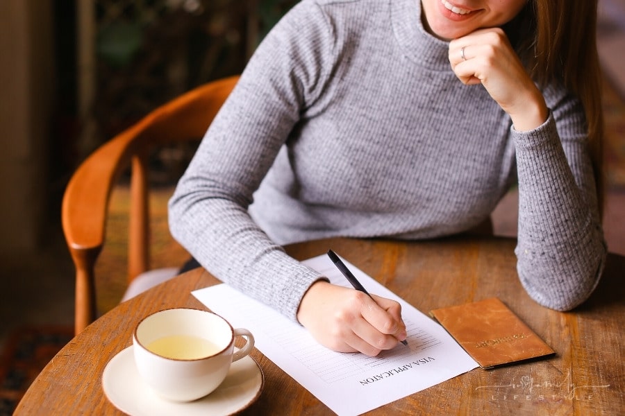 woman filling out visa application with passport nearby