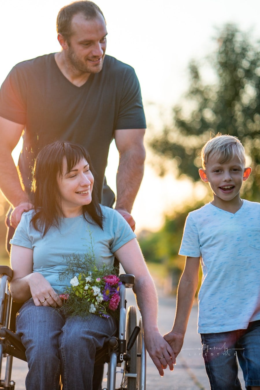 disabled mother walking with her son and husband at sunset