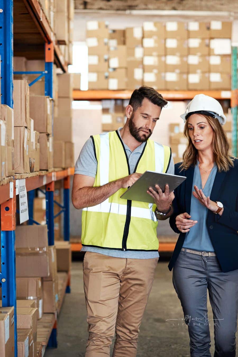 businesswoman walking through a warehouse with a male worker