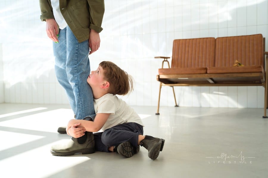 Boy Sitting on the Floor while Hugging a Person's Leg