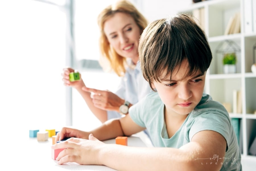 sad child looking away while playing with blocks