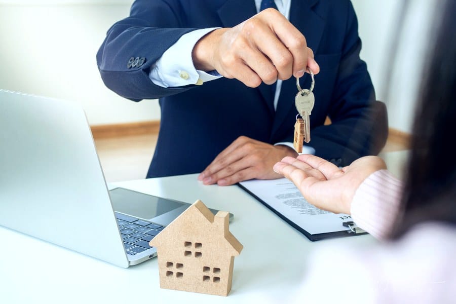 agent holding out new house keys to home buyer