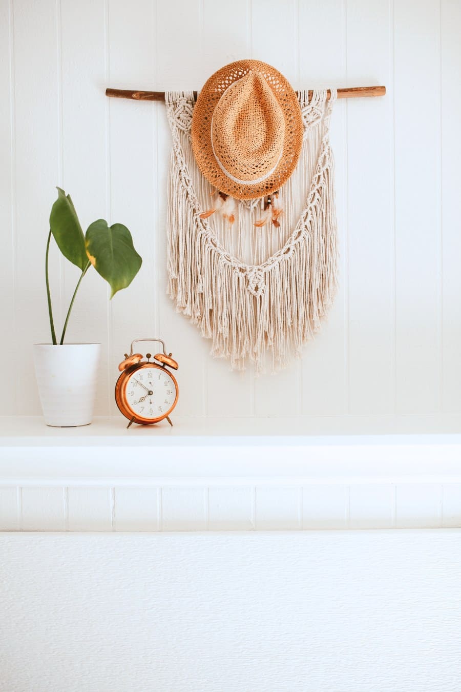 white fireplace with macrame hat hanger above it