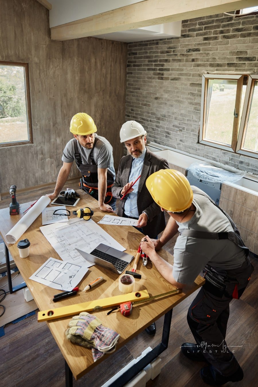 Architect and manual workers talking about home renovation plans.