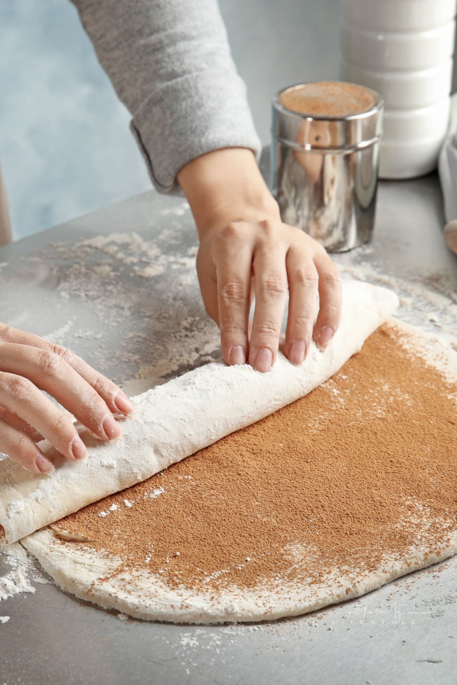Woman Making Cinnamon Rolls at Table, Closeup; rolling dough to form cinnabon