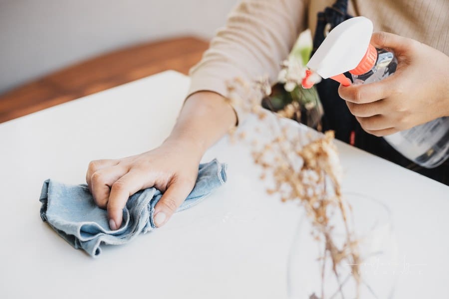 House Cleaner Spraying and Wiping White Table